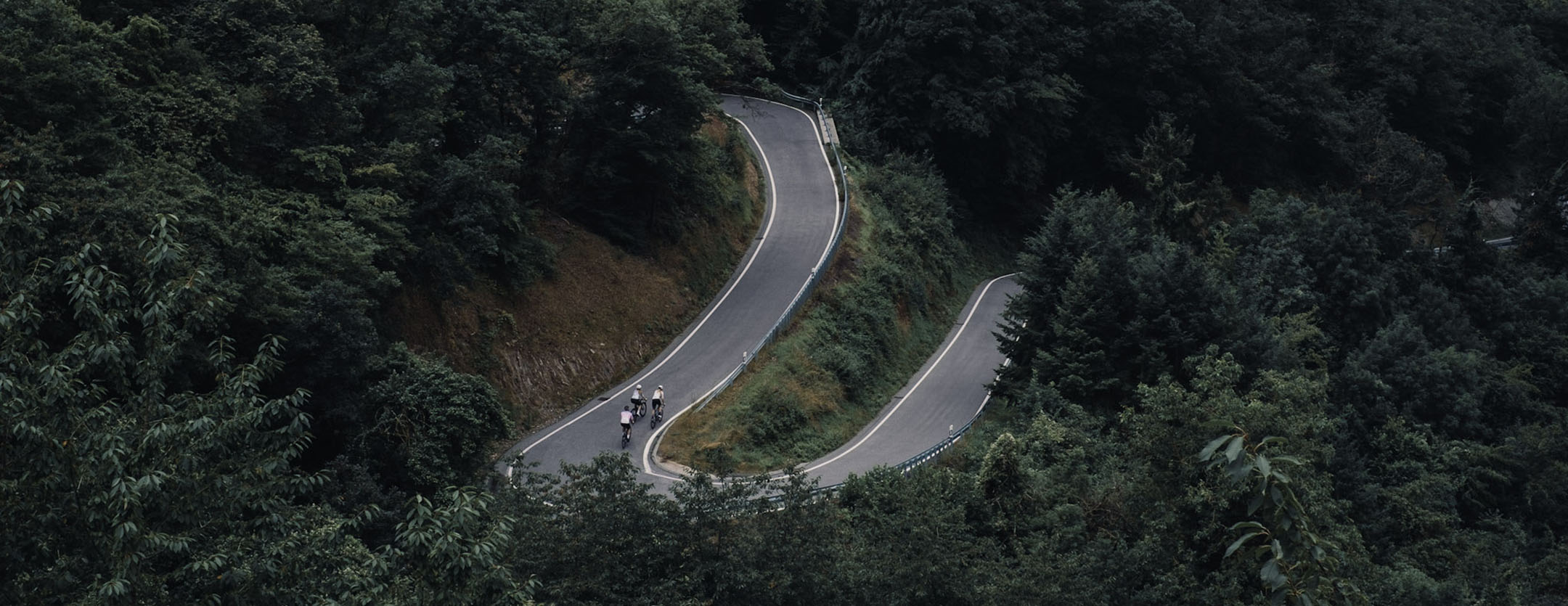 3 Radfahrer fahren Serpentinen an einem Berg mit Radbekleidung von straede